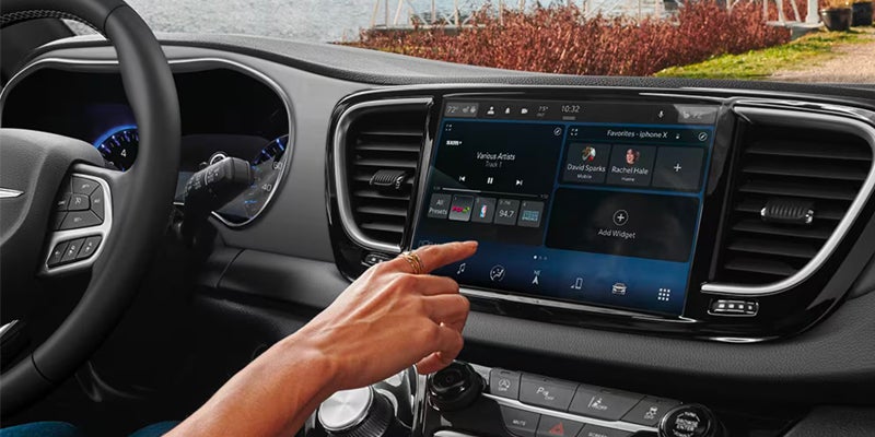 Person interacting with a vehicle's touchscreen infotainment system from the driver's seat