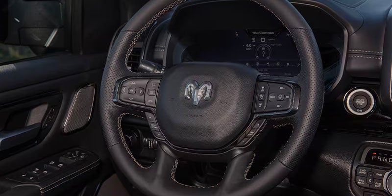 The dashboard and steering wheel of a Ram truck, featuring a dashboard screen and start/stop button.