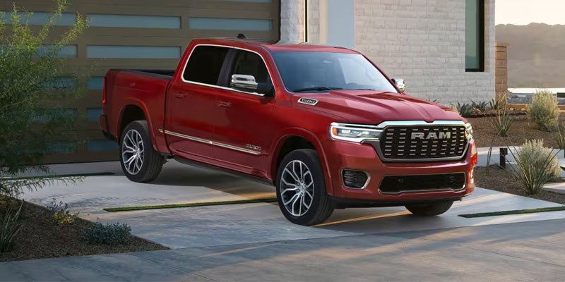 A red Ram pickup truck parked on a driveway in front of a modern garage and house.