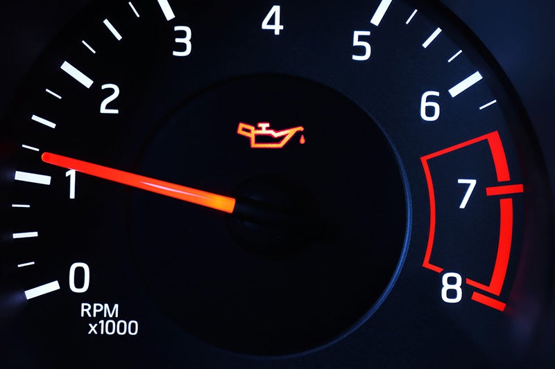 Vehicle tachometer displaying an illuminated oil pressure warning light on the dashboard