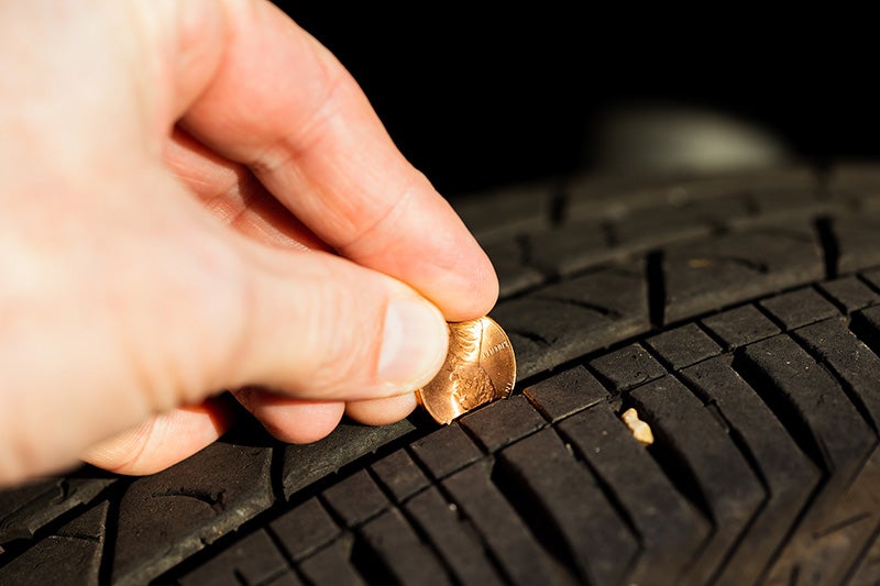 Close-up of a coin inserted into a tire tread groove to check tire tread depth and assess tire wear